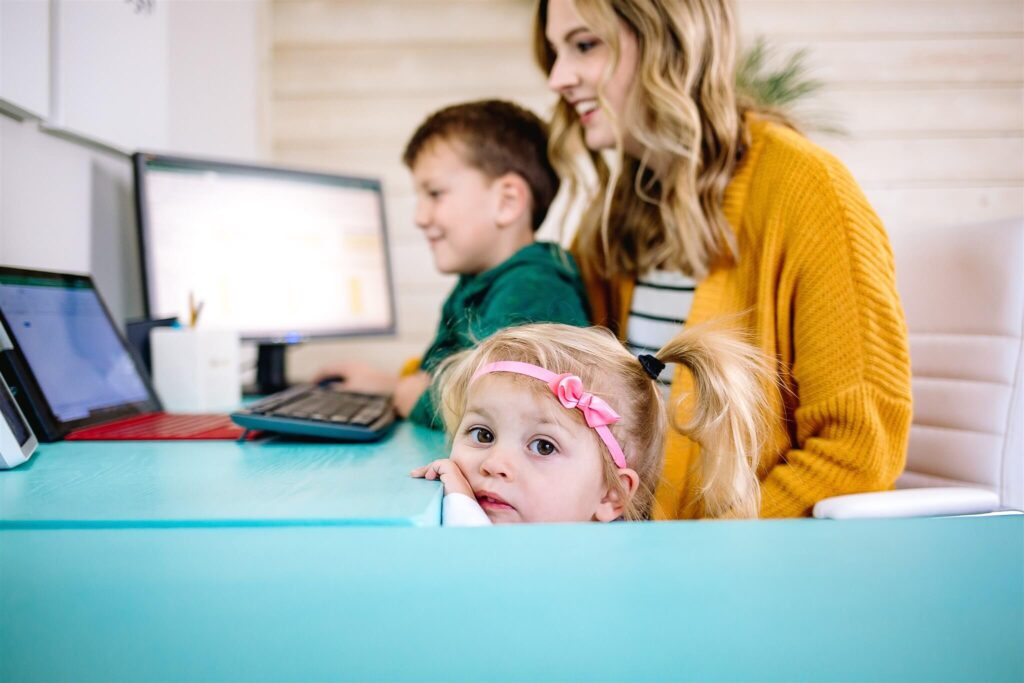 Fempreneur Jamie Trull working at her desk with her two young children nearby—capturing the blend of motherhood and entrepreneurship in a home office setting.