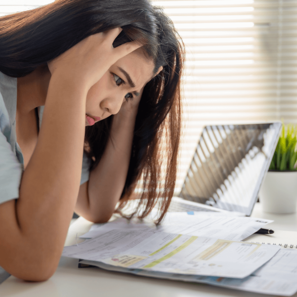 A woman sitting at a desk looking concerned, with papers and calculations scattered around.

A visual metaphor representing the concept of stressful tax liability, the total amount of taxes owed to the government by an individual or entity.