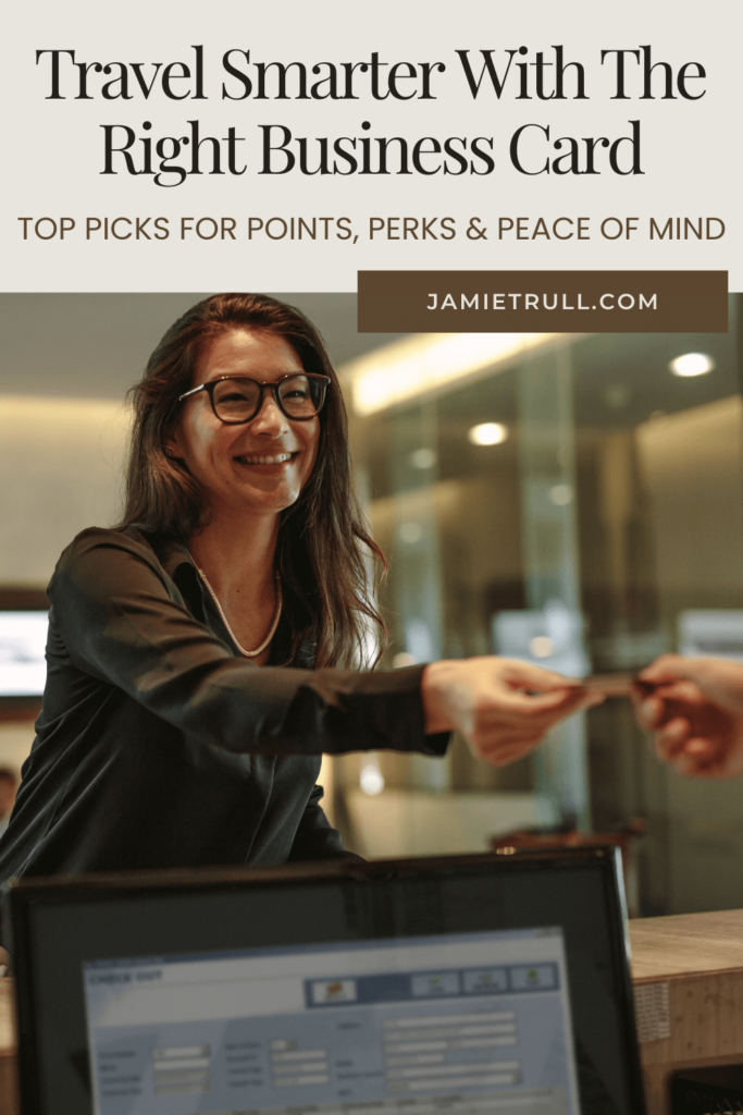 A smiling woman hands over her credit card at a hotel front desk, symbolizing business travel perks such as waived foreign transaction fees and benefits with car rental partners. A check-in screen is visible in the foreground.