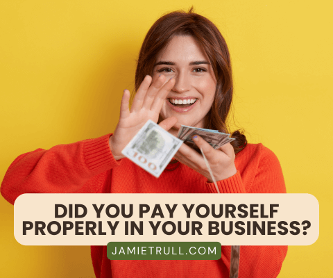 A smiling woman in a red sweater holds cash in her hand against a bright yellow background. The text overlay reads, "Did you pay yourself properly in your business?" with the URL "JAMIETRULL.COM" below. The image emphasizes the importance of managing taxable income effectively as a business owner