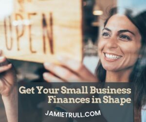 Smiling business owner hanging an “open” sign, symbolizing business operations, managing labor budget, tracking revenue, projected revenue, and net income.